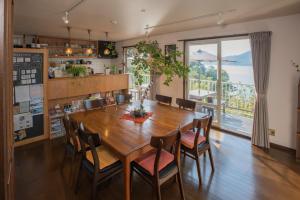Sen Guesthouse في شودوشيما: غرفة طعام مع طاولة وكراسي ونافذة كبيرة