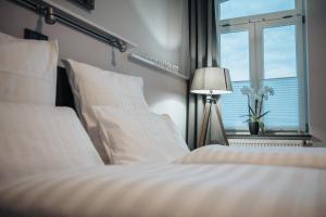 a bedroom with a bed with white sheets and a window at Hotel & Restaurant Christian IV in Glückstadt