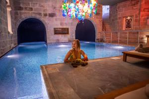 una joven sentada en una piscina en Imperial Cave Suites & Spa, en Göreme