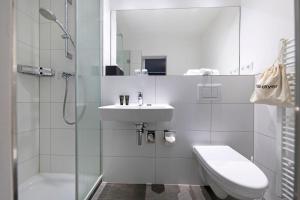a bathroom with a sink and a toilet and a shower at Hotel Meerzeit in Scharbeutz