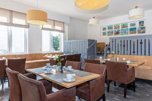 un ristorante con tavoli e sedie in legno e finestre di Hotel Meerzeit a Scharbeutz