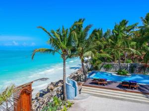 a pool on the beach with palm trees and the ocean at Casa Paradis in Jambiani