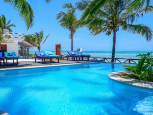 a swimming pool with palm trees and the ocean at Casa Paradis in Jambiani