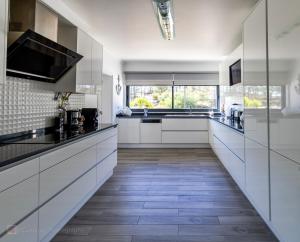 a kitchen with white cabinets and a wooden floor at Home Beach Dream House in Carvalhal