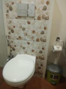 a bathroom with a toilet and a rock wall at Meritas Seawind Beach Resort, Shrivardhan in Srīvardhan