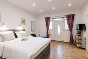 a bedroom with a large white bed and a window at Apartments Martha in Dubrovnik