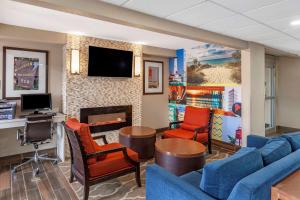 sala de estar con sofá azul, sillas y TV en Clarion Pointe Racine - Mount Pleasant, en Racine