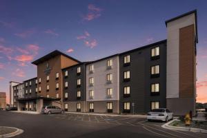 un edificio con coches estacionados en un estacionamiento en WoodSpring Suites Tri-Cities Richland, en Richland