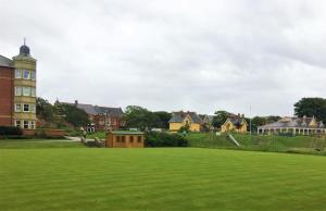 a large green field with houses in the background at Woodlands Holiday Apartments in Lytham St Annes