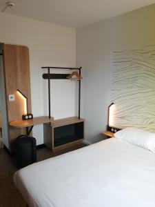 a hotel room with a white bed and a shelf at B&B HOTEL Ouistreham in Ouistreham