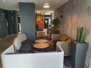a lobby with chairs and tables in a room at B&B HOTEL Ouistreham in Ouistreham