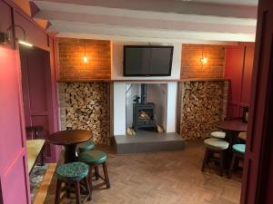 a bar with a fireplace and stools and a tv at The White Horse in Cranswick