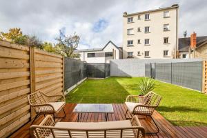 a backyard with a wooden deck with chairs and a lawn at Maison Elleviou - Grande Maison à deux pas du centre in Rennes