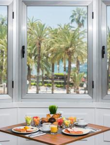 una mesa con platos de comida y una ventana con palmeras en Hotel Alicante Gran Sol, affiliated by Meliá, en Alicante