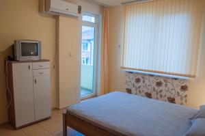 a bedroom with a bed and a tv and a window at Edelvais Guest House in Primorsko