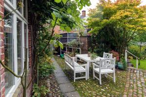 een patio met een tafel en stoelen in een tuin bij To sammenhængende værelser med udgang til have in Ribe
