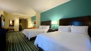 a hotel room with two beds with white sheets at Holiday Inn Express Hotel & Suites Orlando East-UCF Area, an IHG Hotel in Orlando