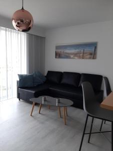 a living room with a black couch and a table at Apartment Green Garden in Middelkerke