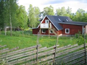 a red barn in a field with a fence at Loft Ålaryd in Skillingaryd