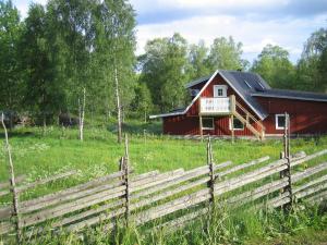 a red barn in a field with a fence at Loft Ålaryd in Skillingaryd