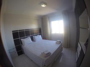 um quarto com uma cama com lençóis brancos e uma janela em Golden Dolphin GrandHotel em Caldas Novas