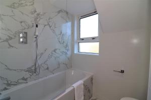 a white bathroom with a tub and a marble wall at Jess View in Renfrew