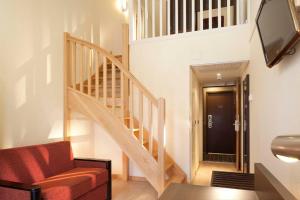 a living room with a staircase and a red chair at Hôtel AKENA Biarritz - Grande plage in Biarritz