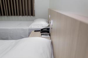 une chambre avec deux lits et une table avec deux téléphones dans l'établissement Hotel Vitoria - Itajaí, à Itajaí