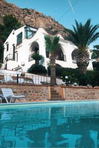a house with palm trees in front of a swimming pool at Villa del Golfo Urio with swimming pool shared by the two apartments it is essential to have a car in Santa Flavia