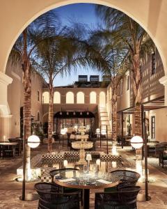 um pátio com mesas e cadeiras e palmeiras em Katikies Garden Santorini - The Leading Hotels Of The World em Fira