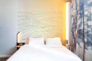 a bedroom with a white bed and a wall at B&B HOTEL Ouistreham in Ouistreham