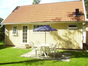 a table and chairs with an umbrella in front of a house at DeLay's Guest House in Ängelholm