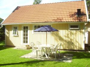 una mesa y sillas con sombrilla frente a una casa en DeLay's Guest House, en Ängelholm