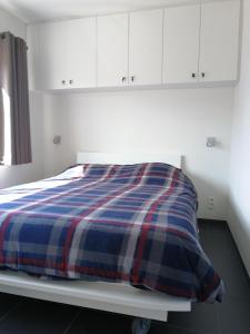a bed with a blue and red plaid blanket on it at Marjolaine Zeezicht - Nieuwpoort-bad met GRATIS garagebox in Nieuwpoort