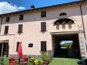 un grand bâtiment rose avec une porte et une terrasse dans l'établissement B&B Happiness in the Country, à Brescello