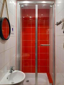 W łazience znajduje się prysznic, umywalka i czerwone kafelki. w obiekcie W Rynku we Wrocławiu