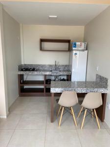 uma cozinha com um balcão, um frigorífico e 2 cadeiras em Delú Residences em Alto Paraíso de Goiás