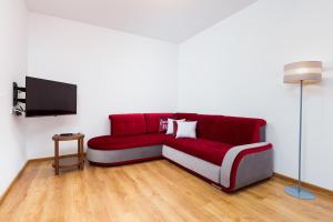 een rode bank in een woonkamer met een tv bij Mokotow Business Center Apartments by Renters in Warschau