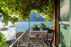 una mesa y una silla en un balcón con vistas al agua en Casa Pergola, en Varenna 13 fotos más