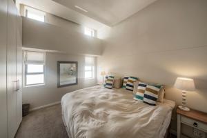 ein Schlafzimmer mit einem großen Bett mit Kissen darauf in der Unterkunft Surferscorner Self Catering Apartments in Muizenberg