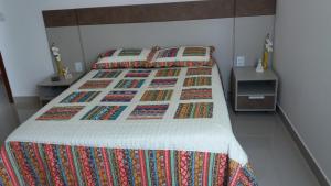 a bed with a colorful quilt on it in a bedroom at Quarto da GABI in Capitólio
