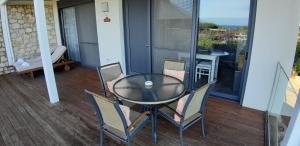 a glass table and chairs on a balcony at Artemis Village Apartments & Studios in Stavros