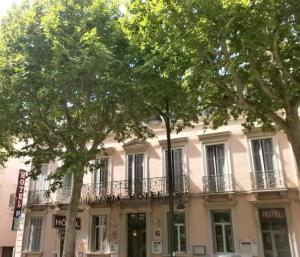 um edifício com árvores em frente em Hôtel Le Victoria em Draguignan