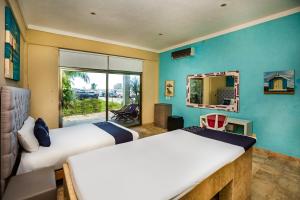 two beds in a room with a mirror and a window at Capital O Cancun International Airport 24 p 7 in Cancún