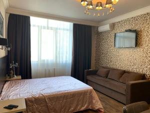 ein Schlafzimmer mit einem Bett, einem Sofa und einem Kronleuchter in der Unterkunft Apartment Elegant in Kiew