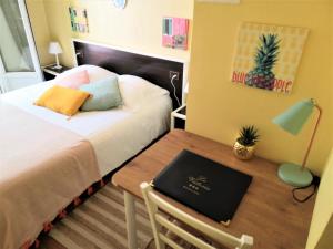 a bedroom with a bed and a table with a laptop at Hôtel Le Victoria in Draguignan