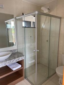 W łazience znajduje się szklana kabina prysznicowa i umywalka. w obiekcie Delú Residences w mieście Alto Paraíso de Goiás