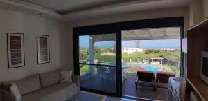 ein Wohnzimmer mit einem Sofa und einer Glasschiebetür in der Unterkunft Artemis Village Apartments & Studios in Stavros