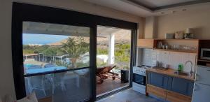 eine Küche mit einer Glasschiebetür, die auf eine Terrasse führt in der Unterkunft Artemis Village Apartments & Studios in Stavros