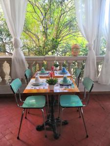 una mesa de madera con sillas verdes en una habitación en Hôtel Le Victoria, en Draguignan